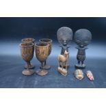 A pair of carved Ashanti fertility figures, a set of four carved goblets and other carved items. H.