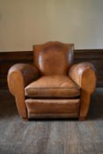 A vintage club armchair in piped tan leather upholstery. H.87 W.97 D.97cm (seat height.40cm)