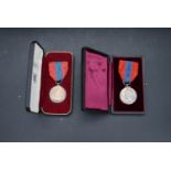 Two leather effect cased silver Imperial service medals on red and blue silk ribbons. One in a Royal
