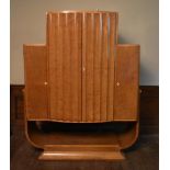 An Art Deco burr walnut cocktail cabinet with ribbed central panel doors enclosing glazed and lit