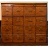 A large vintage oak filing cabinet fitted with a bank of sixteen drawers and a pair of slide out