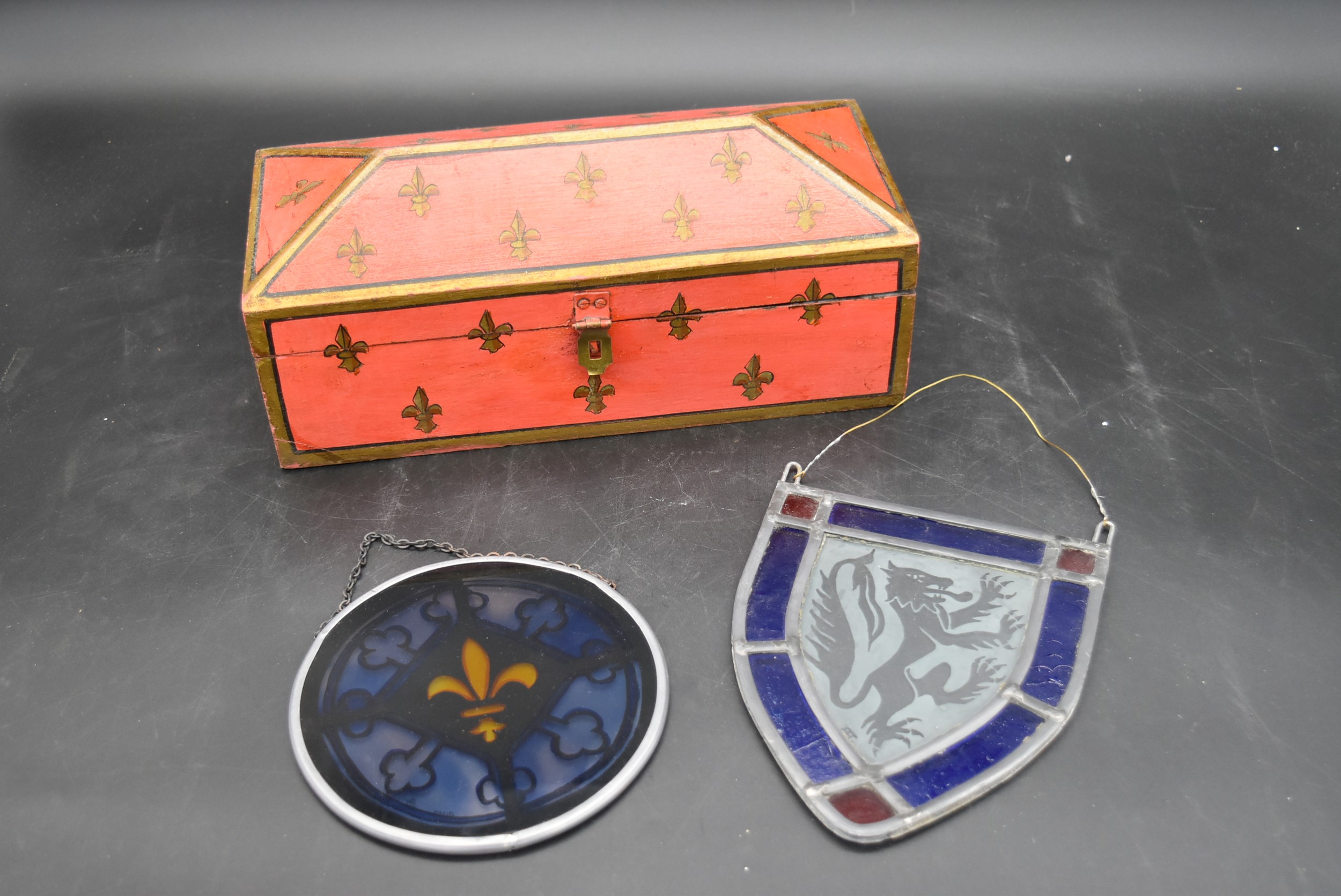 A painted casket with Fleur-de-Lys detail along with two coloured and leaded glass hanging panels.