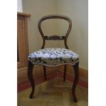 A Victorian carved mahogany balloon back side chair with foliate upholstered stuffover seat on