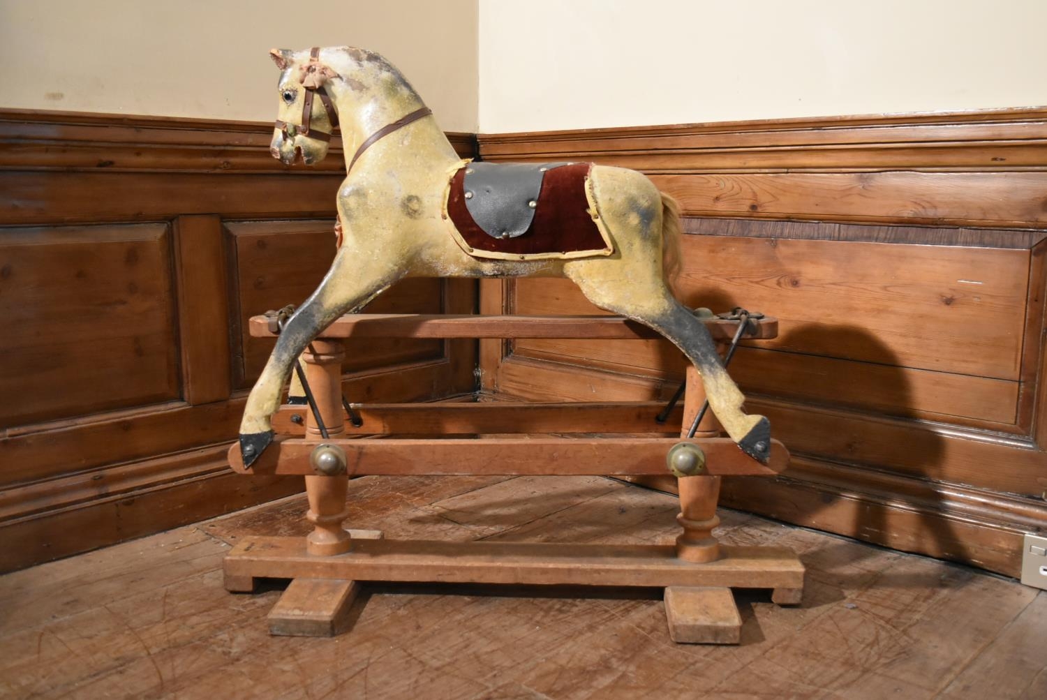 An early 20th century carved and painted Triang rocking horse on swing action oak platform base. H.
