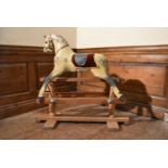 An early 20th century carved and painted Triang rocking horse on swing action oak platform base. H.