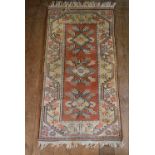 A Milas (Turkey) rug with repeating flowerhead medallions on a salmon ground within scrolling