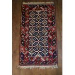 A Kazak rug with repeating stylised flowerhead motifs across the field contained by serrated palm