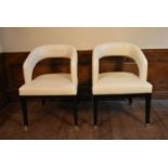 A pair of contemporary hooped back armchairs in piped ivory leather upholstery on ebonised square