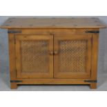 An Eastern teak brass bound side cabinet with rattan panelled doors on block feet. H.62 W.95 D.47.