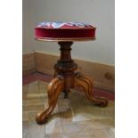 A Victorian walnut piano stool with tapestry embroidered seat on carved tripod base. H.46 Dia.