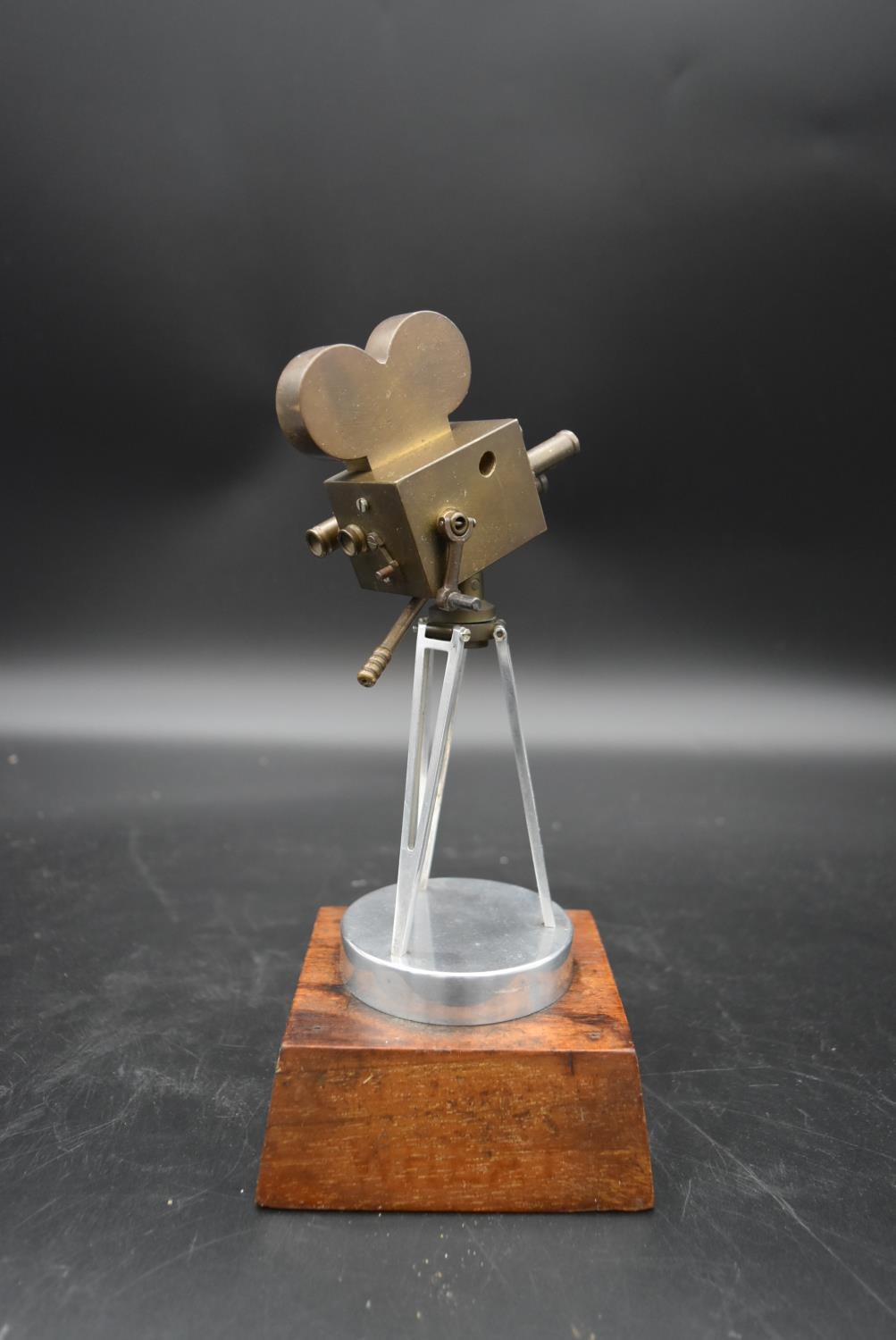 A brass and metal model of a 1930's film camera with hinged head on tripod base standing on wooden - Image 3 of 4