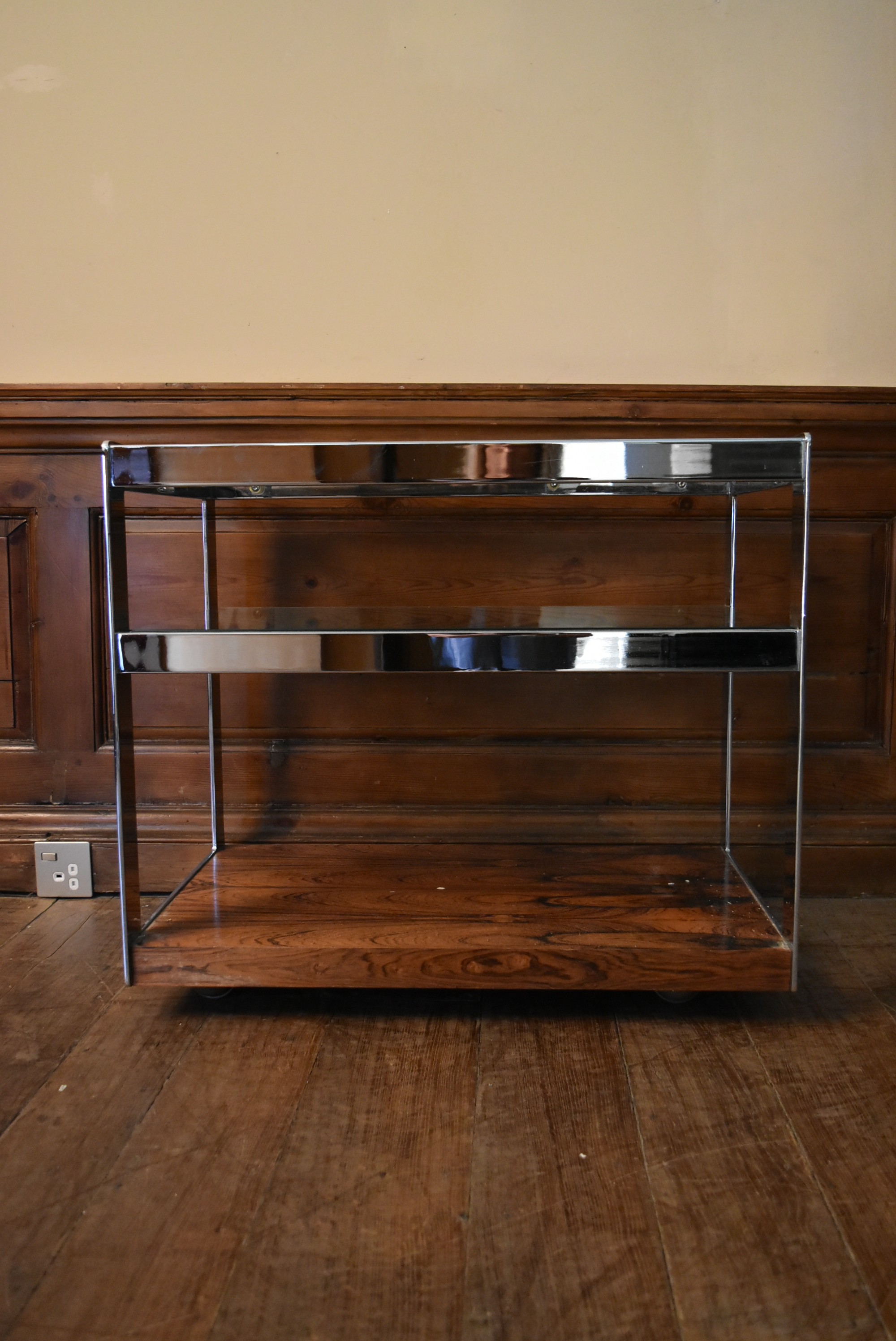 A Merrow Associates chrome framed drinks trolley with plate glass tiers on casters. H.64 W.73 D.46cm