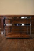 A Merrow Associates chrome framed drinks trolley with plate glass tiers on casters. H.64 W.73 D.46cm