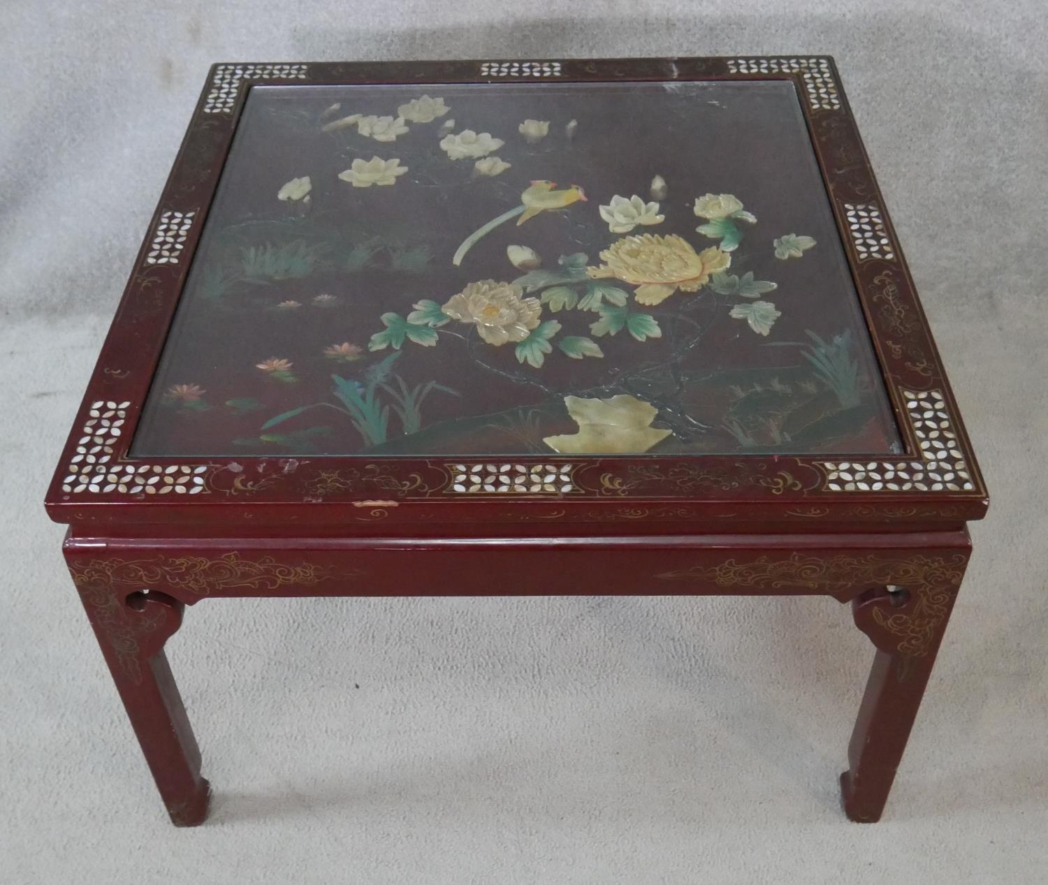 A Chinese black lacquered coffee table with bevelled plate glass drop in top, applied bird and