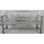 A weathered teak garden bench with central pop up table section. H.88 W.155 D.60cm
