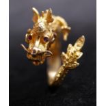 A Chinese 14 carat gold dragon form ring with wire detailing, engraved scales and ruby set eyes.