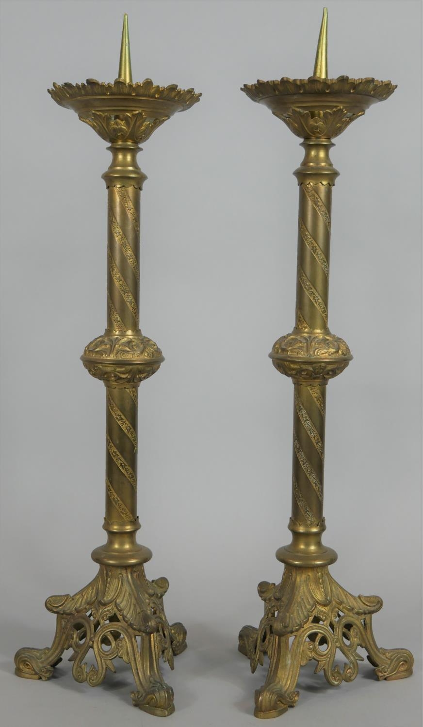 A pair of brass Ecclesiastic style pricket candlesticks on pierced and scrolling tripod bases. H.