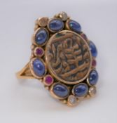A yellow metal (tested as gold) Islamic coin, sapphire, ruby and diamond dress ring. Set to the