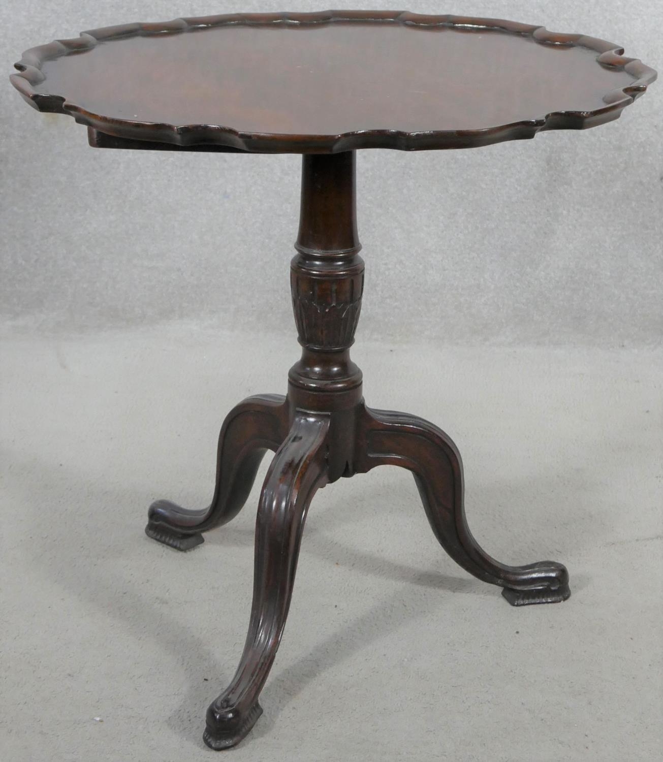 A Georgian style mahogany tilt top occasional table with pie crust edge on husk carved turned