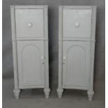 A pair of 19th century pedestal cupboards each with a drawer and arched panelled door flanked by