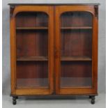 A Victorian mahogany bookcase with arched glazed doors enclosing shelves on turned supports. H.115