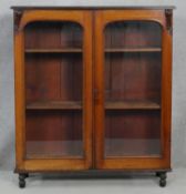 A Victorian mahogany bookcase with arched glazed doors enclosing shelves on turned supports. H.115