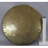 A large oriental hammered brass gong with carrying handle. D.45cm