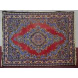 A Persian style carpet with central medallion on a burgundy ground within naturalistic floral