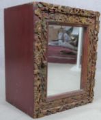 A carved polychrome Eastern teak cabinet with mirrored door. H.43 W.35 D.26cm