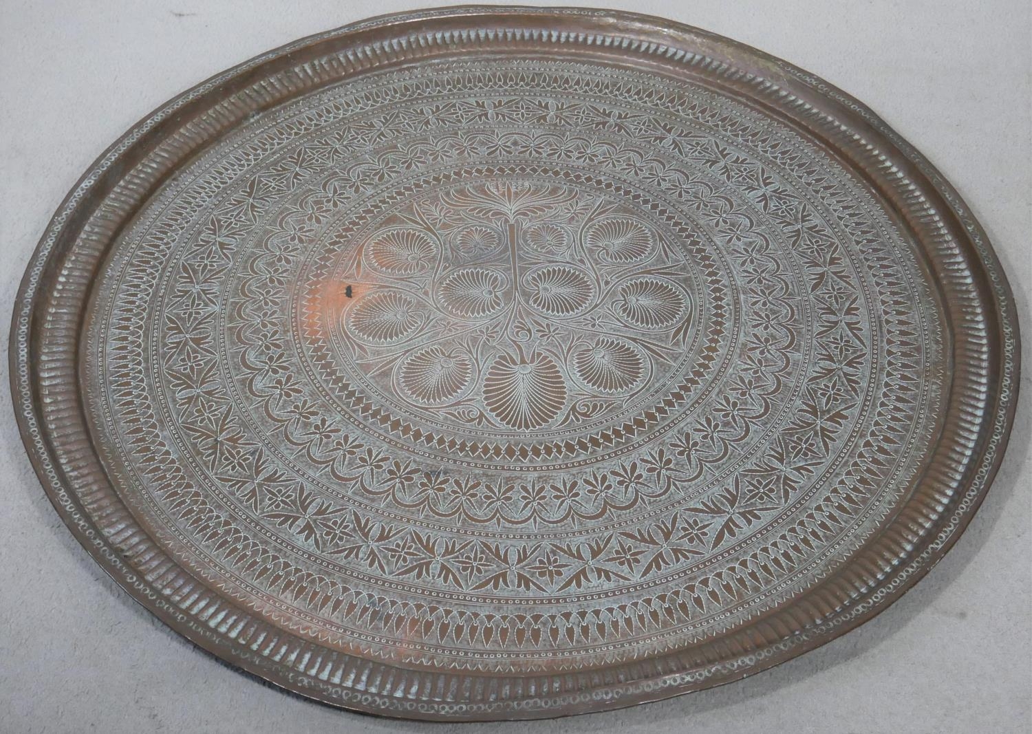 A large brass Eastern engraved tray or table top. D.95cm