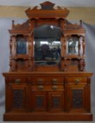 A late Victorian carved walnut mirror backed sideboard with shaped bevelled plates and turned