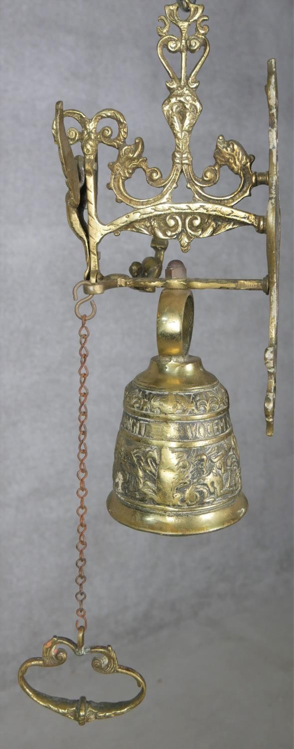 A 20th century French brass gothic style wall mounted bell with relief foliate and figural