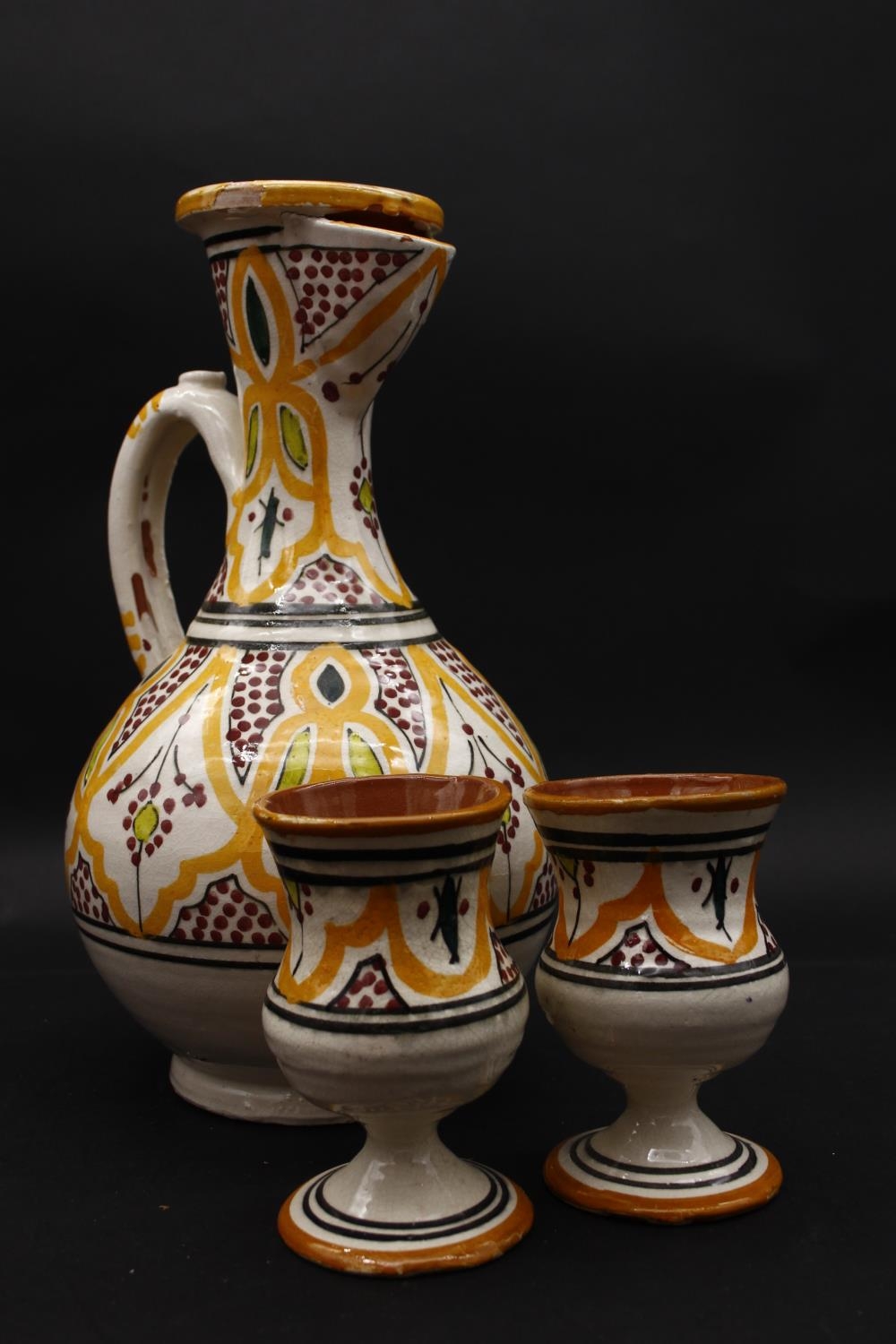 An Islamic glazed hand painted terracotta ewer with stylised foliate and floral design with two