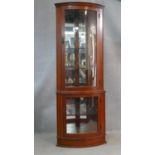 A contemporary mahogany corner cabinet with mirrored back and of bowed outline. H.178 W.65 D.45cm