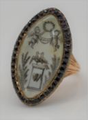 A Georgian red metal mourning ring, the navette-shaped ivory panel painted en grisaille to depict