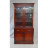 A Georgian style mahogany library bookcase with glazed doors enclosing shelves above frieze drawer