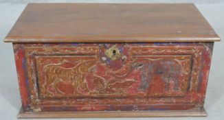 A small Eastern teak coffer with carved and painted animal decoration and twin metal carrying