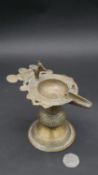 An antique Indian brass oil lamp with peacock design and coiled wire detailing. H.15cm
