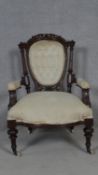 A Victorian buttoned back armchair in carved mahogany frame on fluted tapering supports. H.89cm