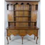 A Georgian style oak dresser with open plate rack fitted with cupboards above three drawers with