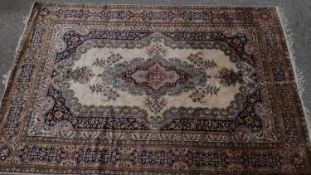 A Persian style carpet with central floral medallion on fawn ground contained by naturalistic floral