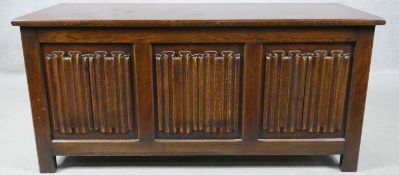 A mid century oak Jacobean style coffer with carved linenfold panels raised om block feet. H.53 W.