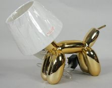 A Jeff Koon inspired table lamp in the form of a gold balloon dog with white shade head. H.30cm