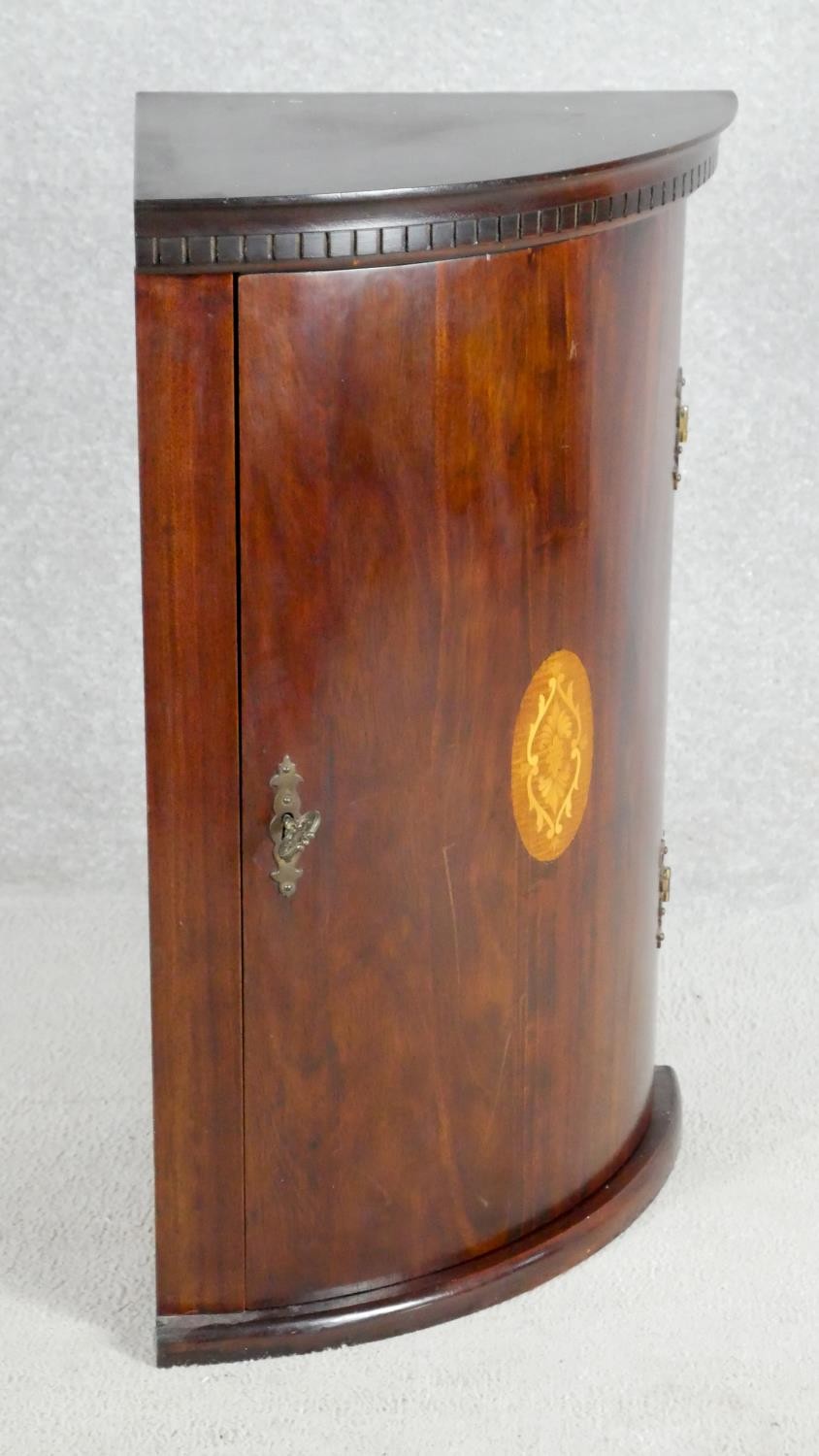 A pair of mahogany Georgian style bow fronted corner cabinets with central satinwood inlay. H.67cm