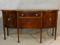 A Georgian mahogany and satinwood crossbanded sideboard of bowed outline fitted with frieze drawer