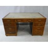 A mid century oak pedestal desk with inset leather top above an arrangement of nine drawers. H.