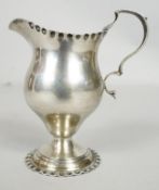 A Victorian sterling silver cream jug with scalloped edge and foot, C-scroll design to the handle.