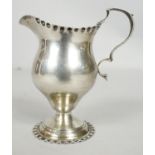 A Victorian sterling silver cream jug with scalloped edge and foot, C-scroll design to the handle.