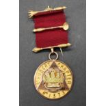 A 9 carat yellow gold St Cutbert Chapter Masonic medal with red silk ribbon. Inscribed 'E. Comp.