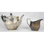 An Edwardian gadrooned silver tea pot and matching milk jug, with ebony finial and handle.